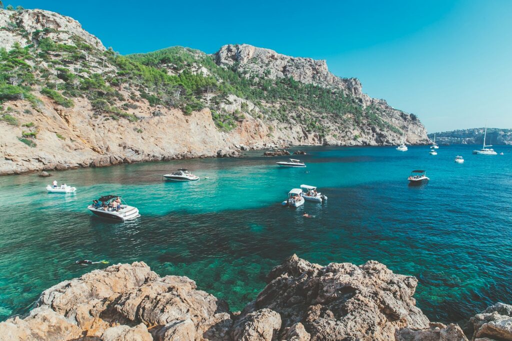 white and blue boat on sea near green mountain during daytime in Mallorca, Spain