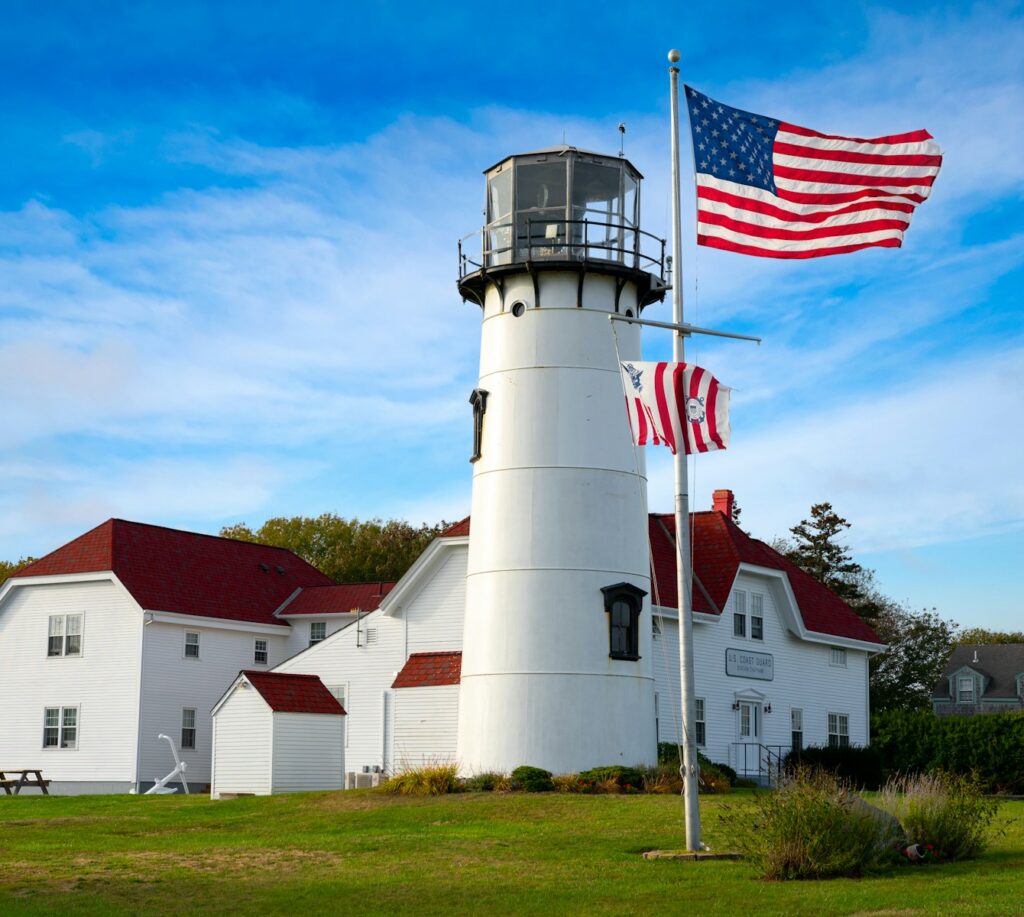 white and red concrete lighthouse near white and red house under blue sky during daytime, memorial day weekend